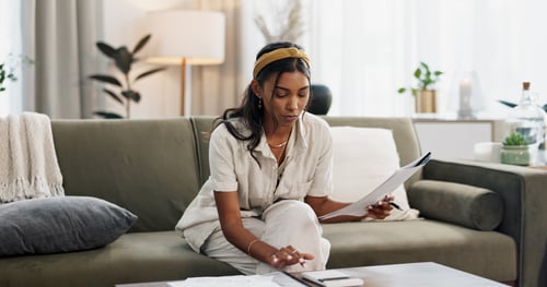 woman on couch looking at financial portfolio paperwork 
