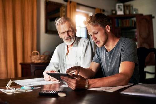 father and son looking at a tablet at home