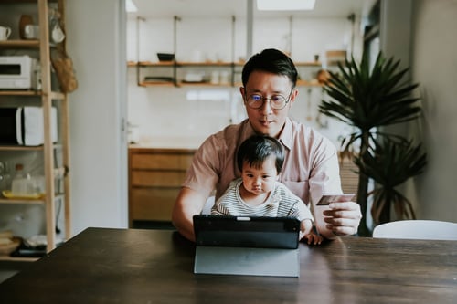 father with child on lap on computer
