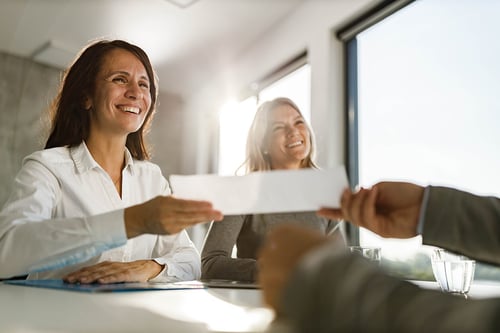 female advisor handing paperwork to client and smiling