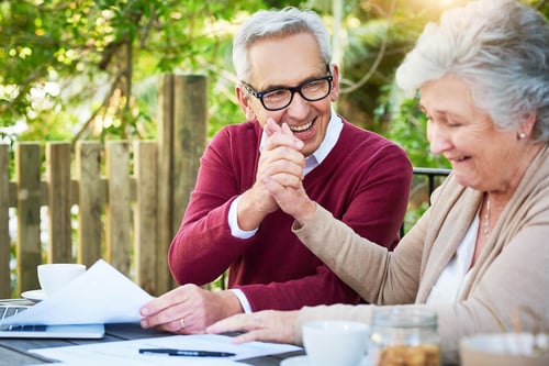 mature couple holding hands while doing paperwork
