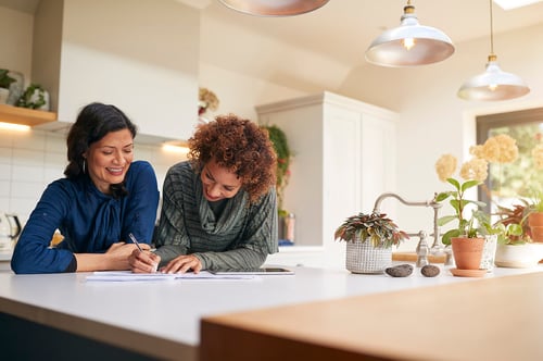 mature female couple reviewing documents in kitchen at home