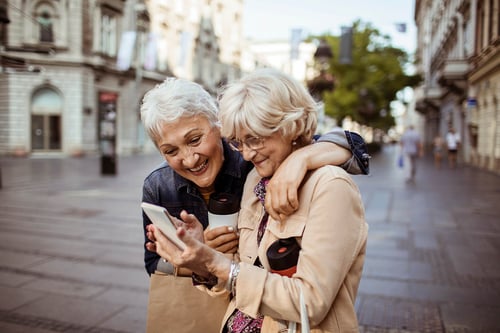 mature female friends in city looking at phone