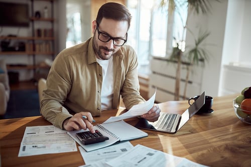 man at a desk doing his taxes with a calculator