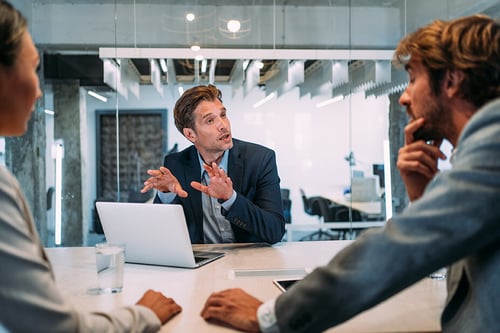 young businessman explaining something to his coworkers in a modern conference room