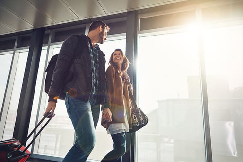 young couple traveling walking with suitcases and smiling