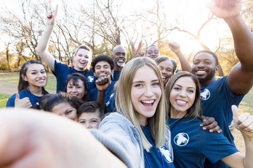 young woman taking a selfie with a group of volunteers